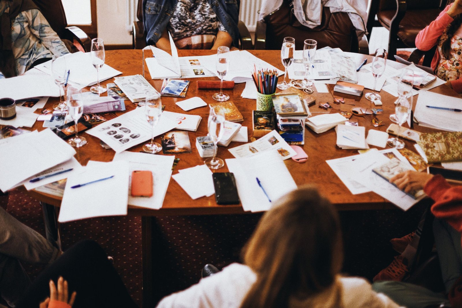 Group collaborating at a cluttered conference table filled with documents and drinks.